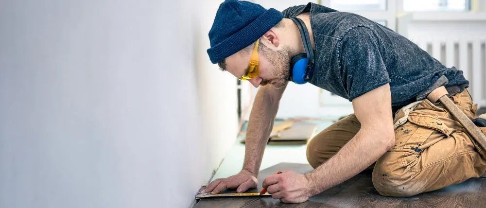Un travailleur du bâtiment effectue une pose de plancher