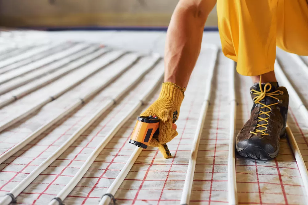 Homme installant un plancher chauffant plus écologique