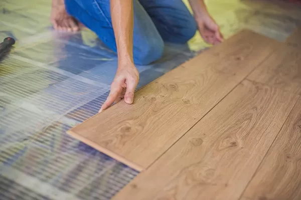 Homme en train d'installer un plancher chauffant